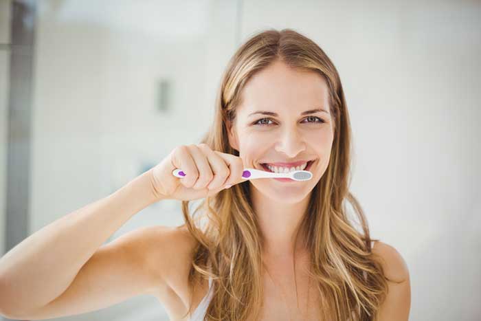 A girl brushing her teeth with Essential Guide