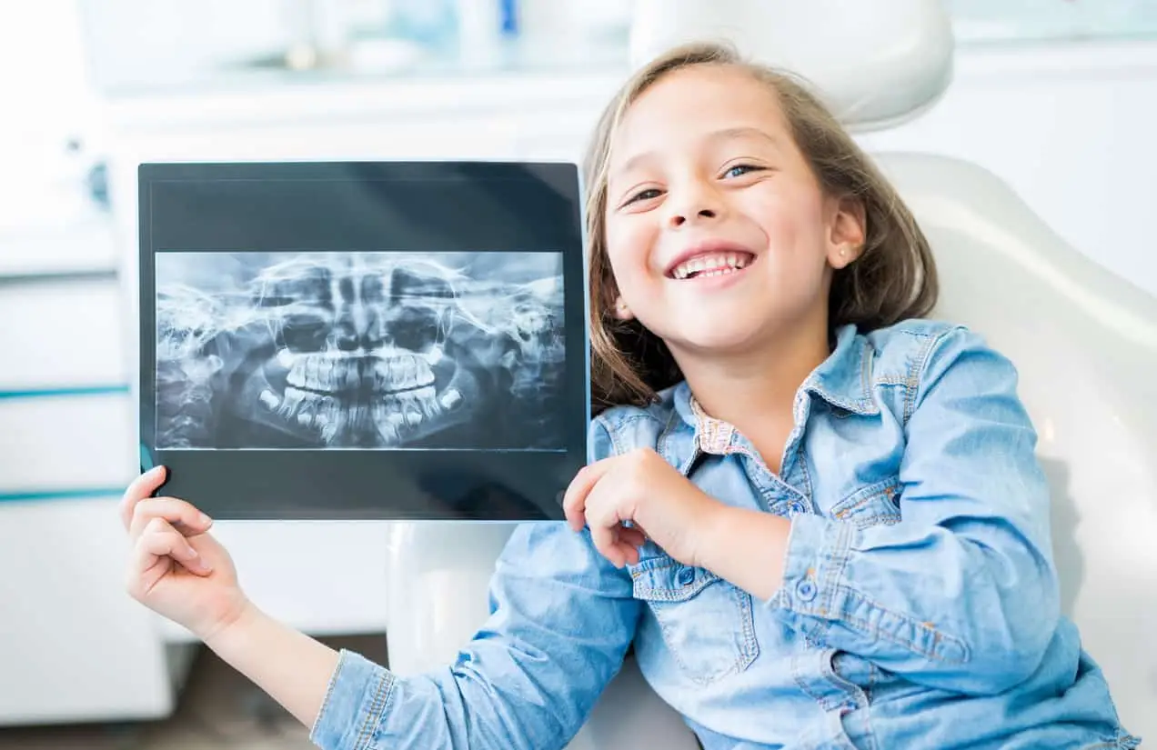 A child at the dentist holding her xrays